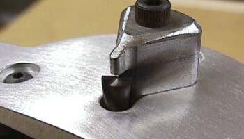 A close-up of the assembled routing guide, showing the bit and the tip of the guide block that sets the thickness of the ledge