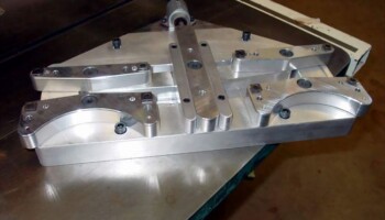 Sometimes when parts can't be held by vacuum, they must be held mechanically. This is a vise that Jim made to "face mill" or smooth one surface and drill the location holes in one fingerbaord or 2 bridge blanks before they can go to the vacuum fixtures. The vise was also drawn in the computer and machined in the Fadal