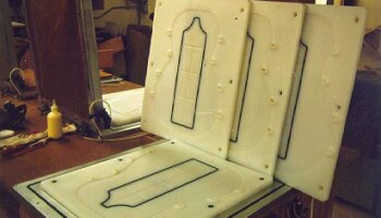 Jim devised this vacuum press for gluing back and top braces in place. The white forms hold backs and braces in place as the glue sets; they are made of UHMW polyethylene machined with the Fadal. Besides the obvious slots around the edge for holding the braces, these back forms are machined with a 15 foot radius to keep the back properly curved. Just visible above the upright forms is the aluminum frame holding a thick rubber top that holds the braces against the back when the vacuum is pulled